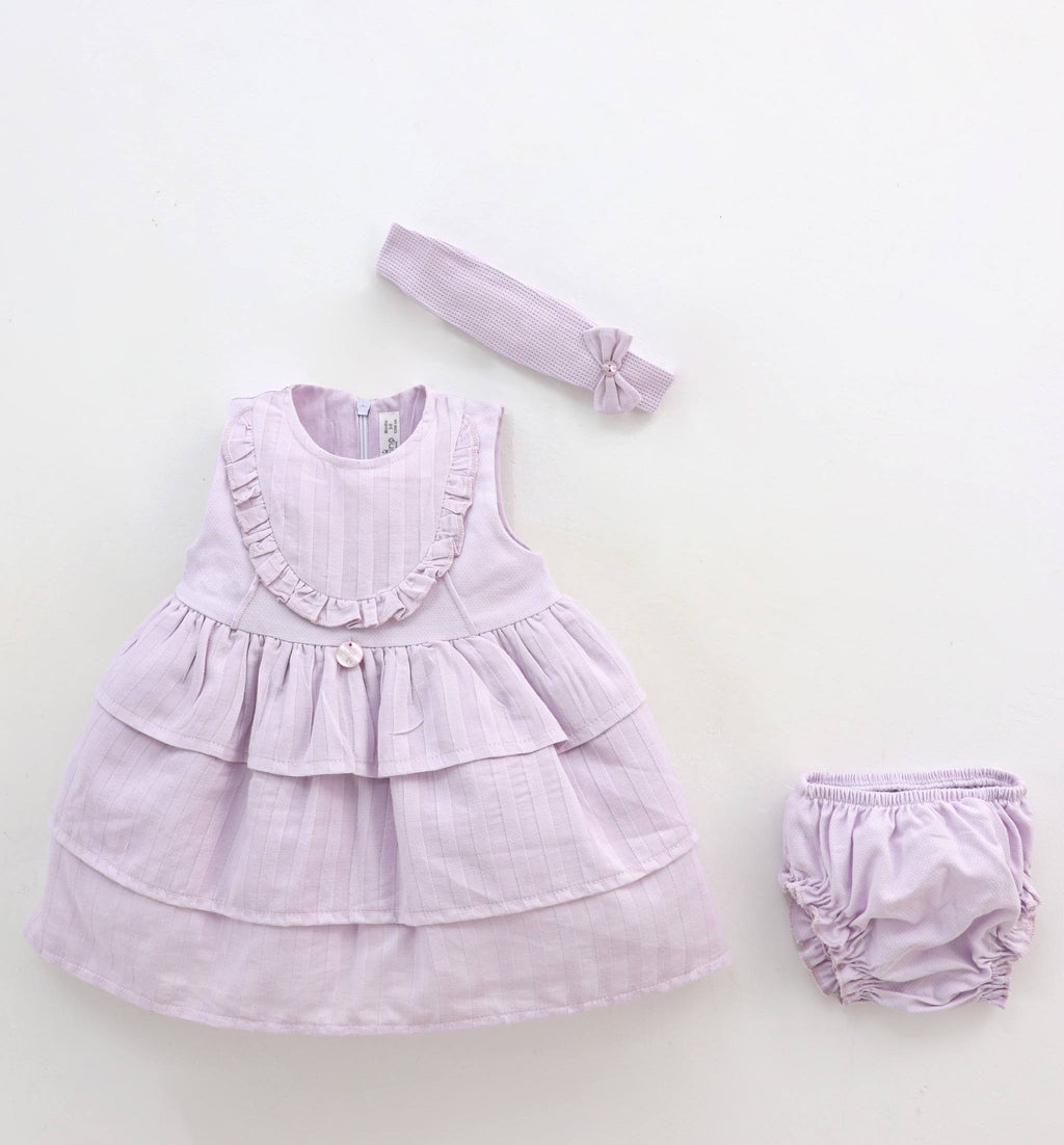 Lavender baby dress with ruffles, matching headband, and bloomers on a white background.
