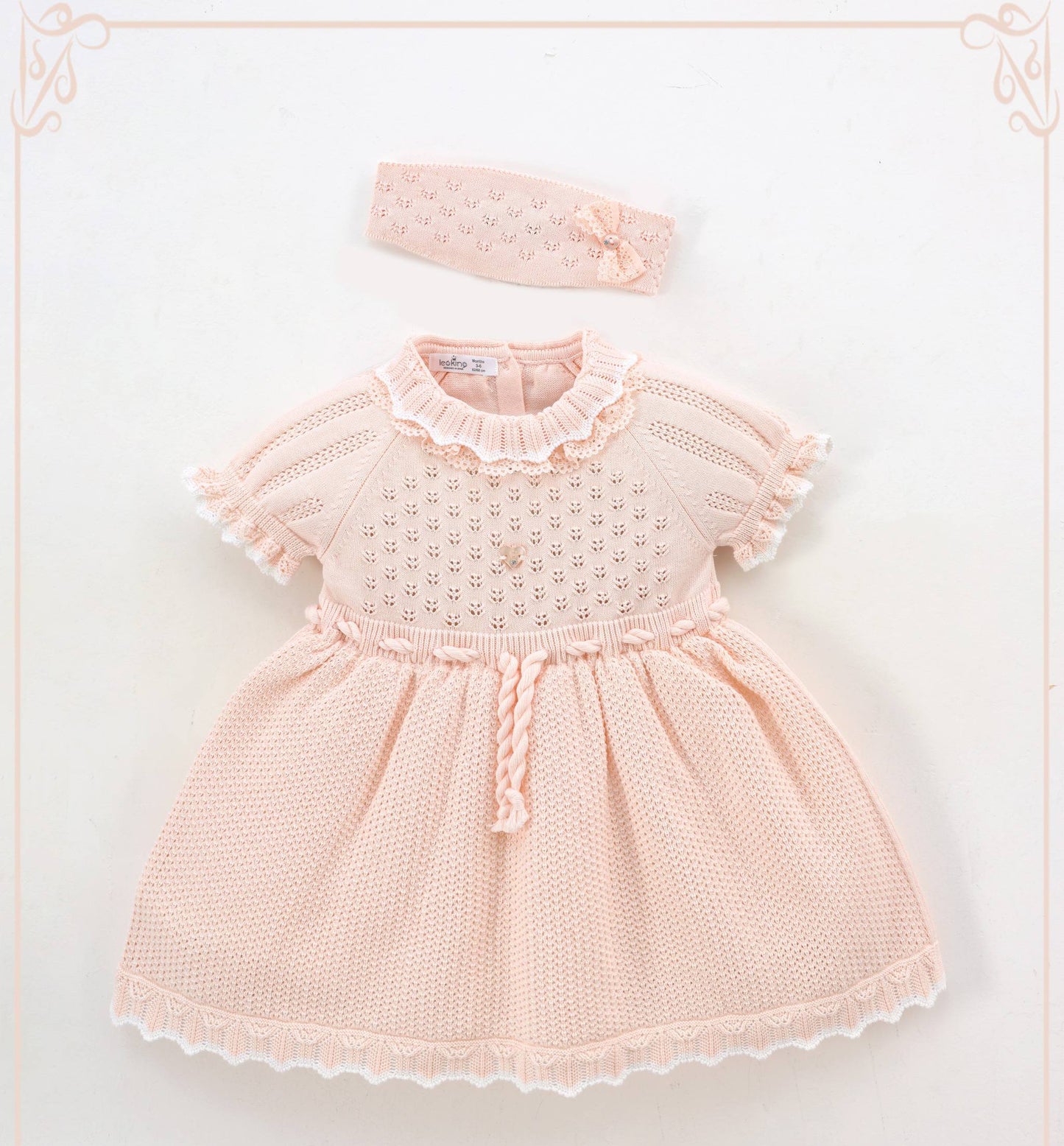 Pink baby dress with ruffled collar and matching headband on a light background